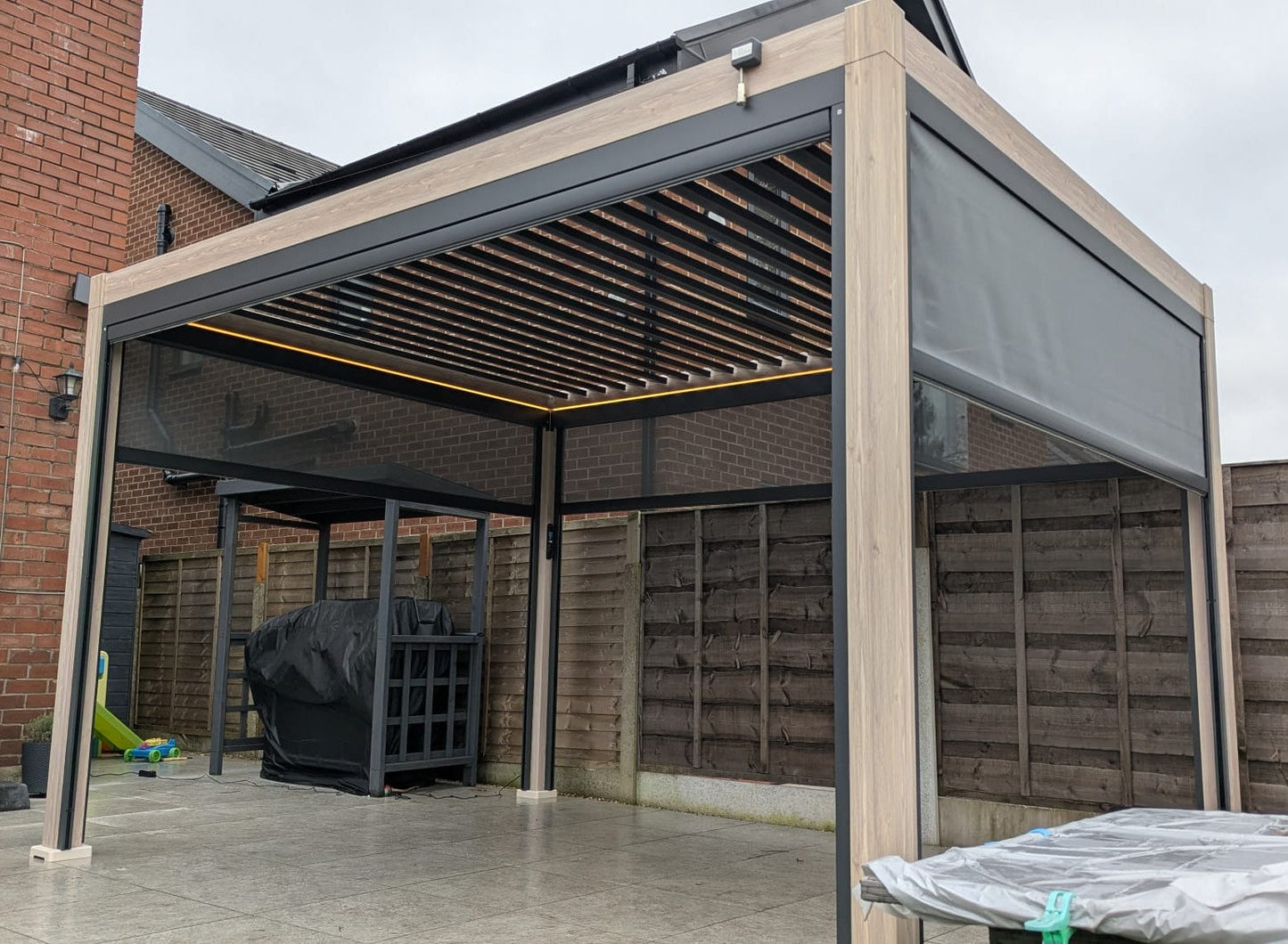 LuxShade™ 3×4m Oak Effect Aluminium Pergola with LEDs, Double-Layered Louvres